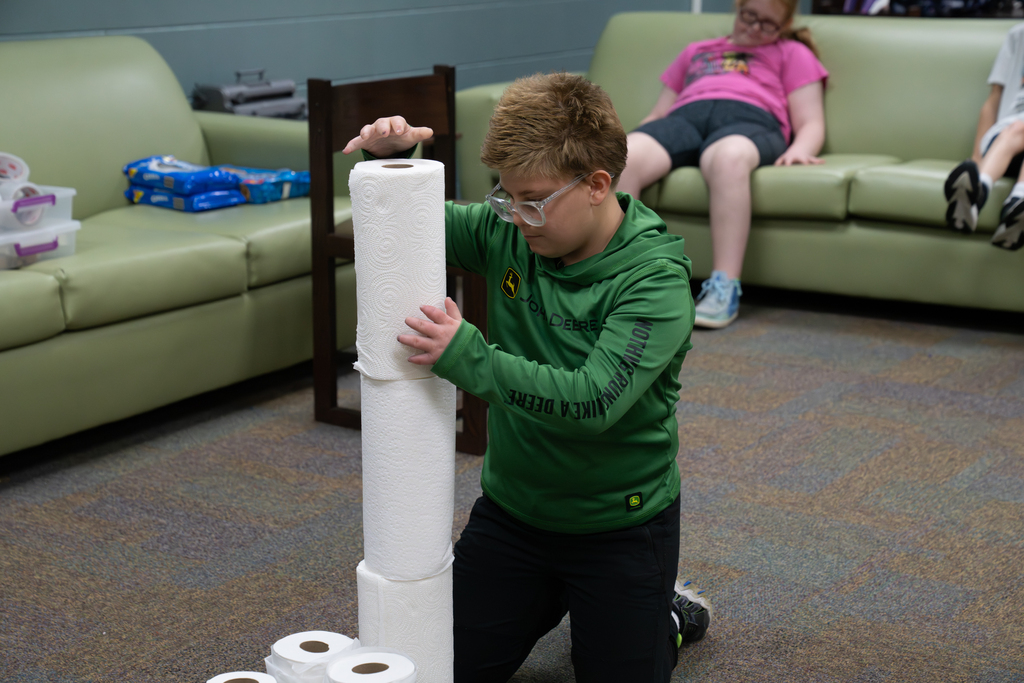 A student is building a tower with paper towels.