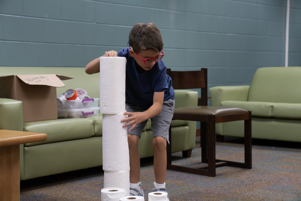 A student is building a tower with paper towels.