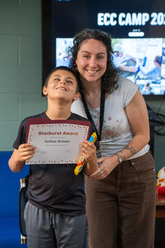 A camera smiles a staff member holding his award and candy inside Cary White.