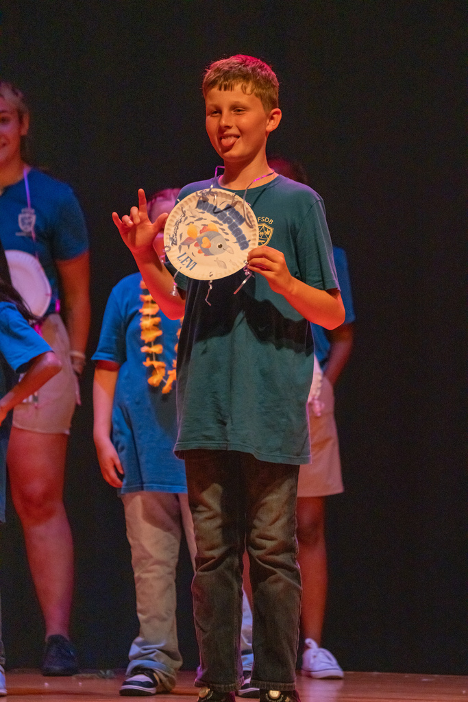 A camper signs I love you and smiles on stage with his award.