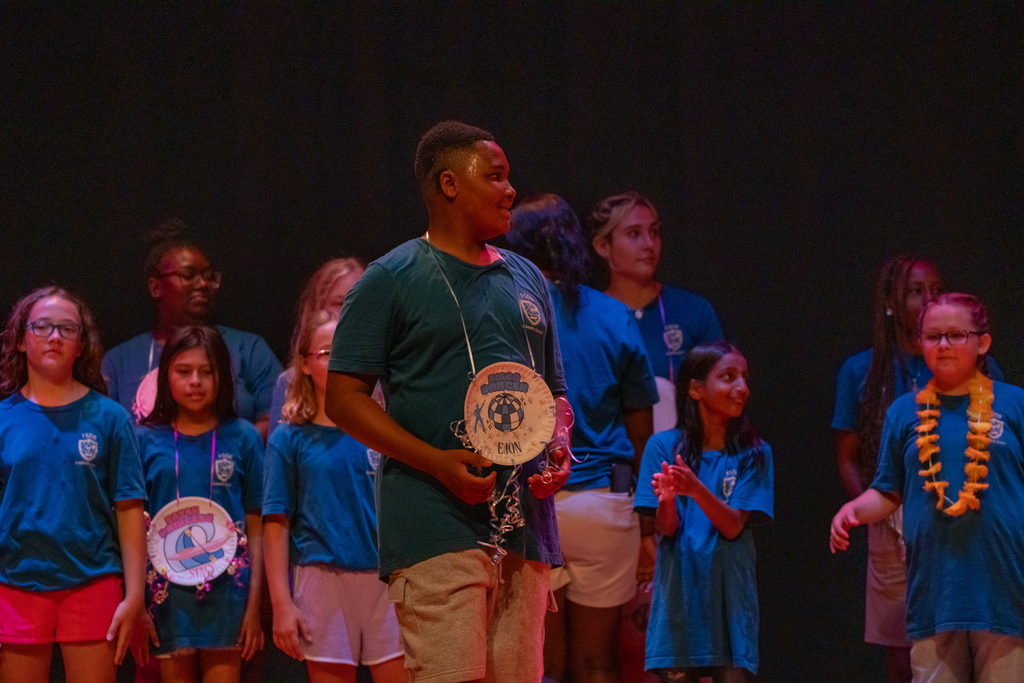 A camper smiles on stage with his award.