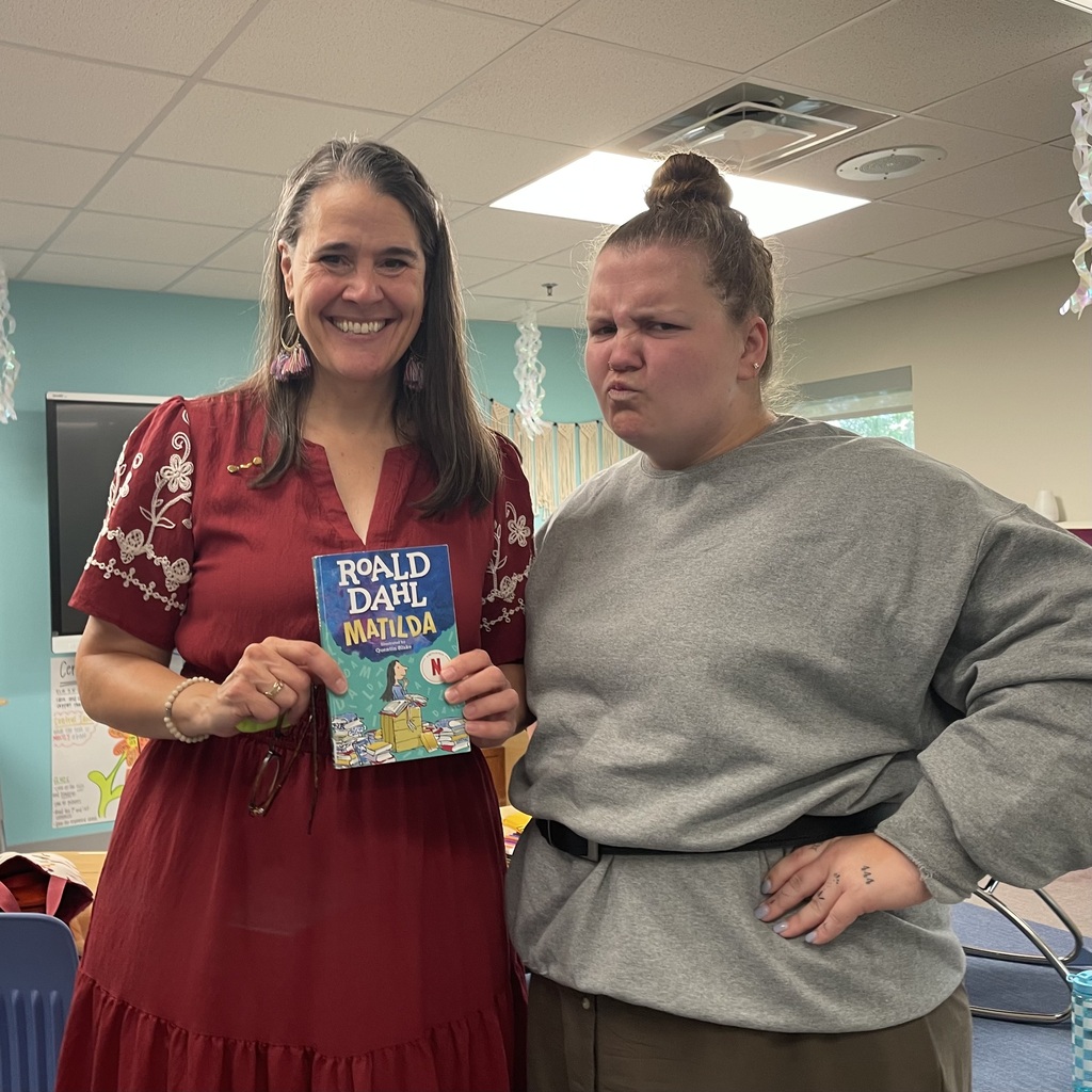 President Snow stands next to Ms. Brady aka Ms. Trunchbull while holding a copy of Matilda.  Ms. Truchbull, true to her character, has her hands on her hips and is scowling at the camera.
