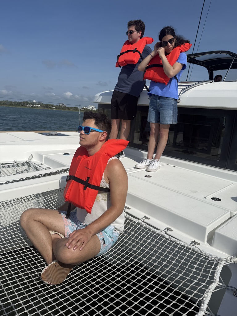 Three campers on the boat wearing red life guard jackets. 