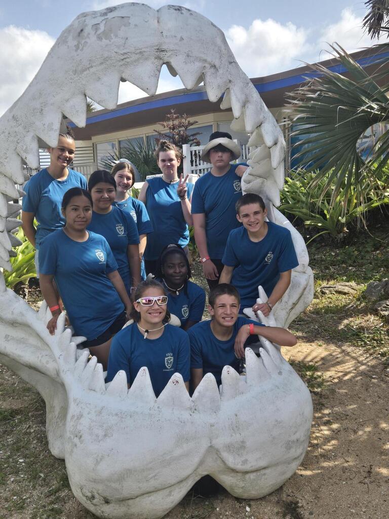 Group of campers smile for a photo together inside the shark teeth mouth.