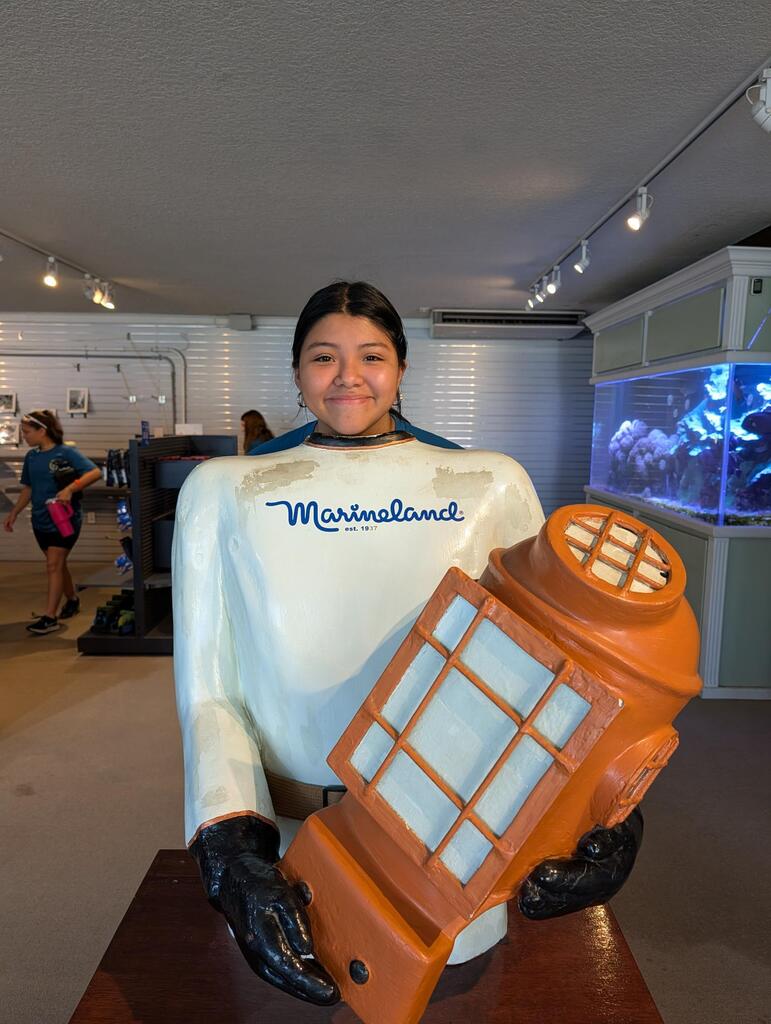 A student smiles behind a statue inside Marineland. 