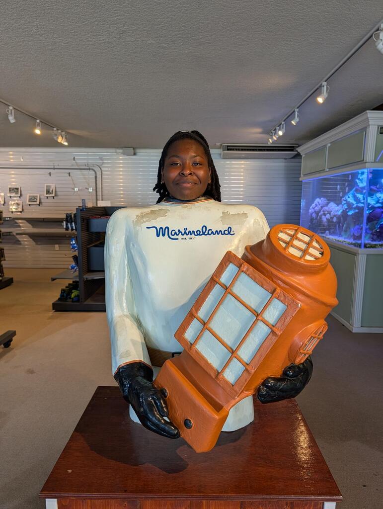 A student smiles behind a statue inside Marineland. 
