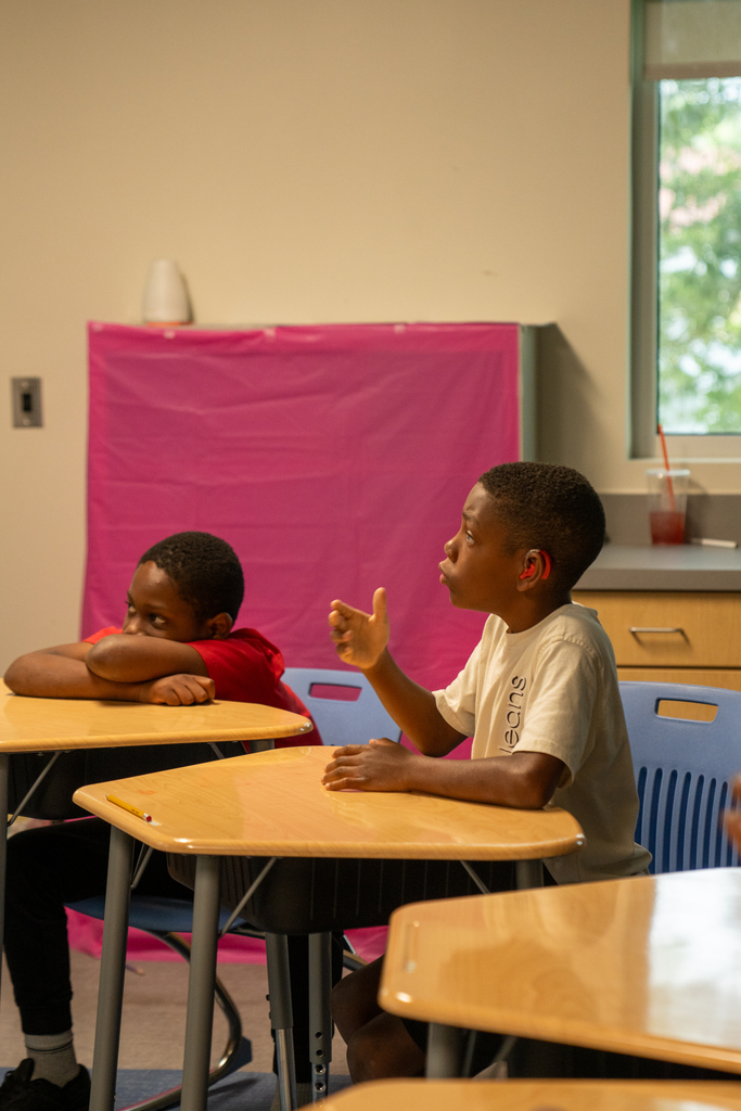 Two students watch the teacher and listening to the teacher. 