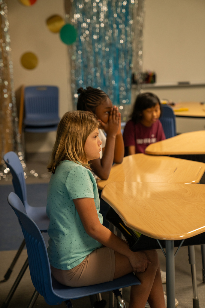 A side angle of students listening to each other at their desks inside the classroom. 