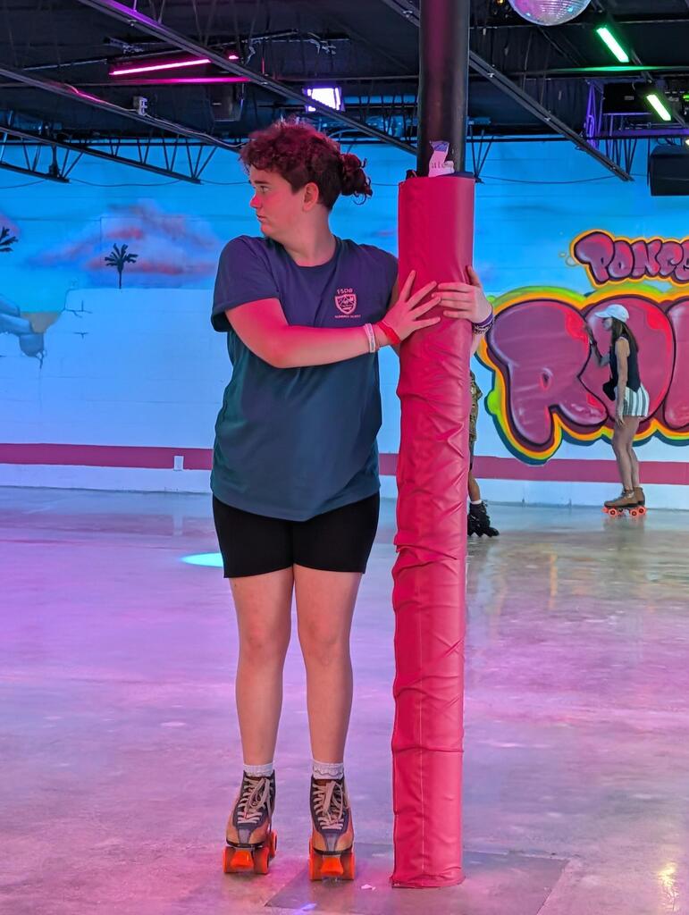 A student holds onto the pole as he is learning to skate. 