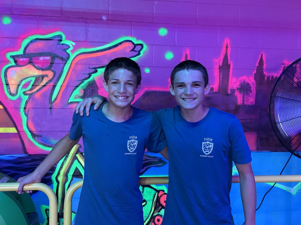 Two campers smile together for a photo inside the skating rink.