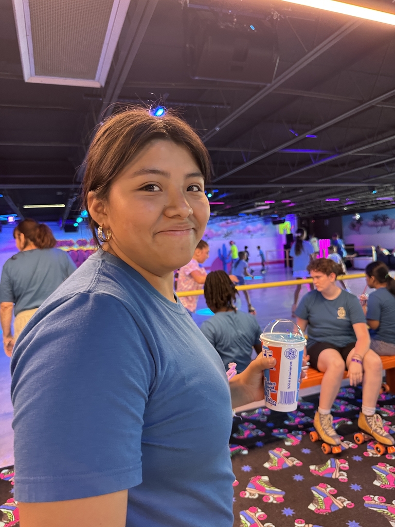 A camper smiles with her slushie at the skating rink. 