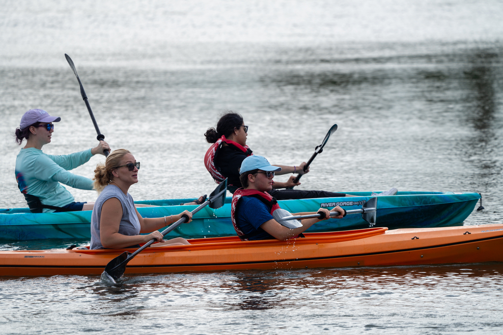 Two sets of campers and staff members inside the kayaks out on the water. 