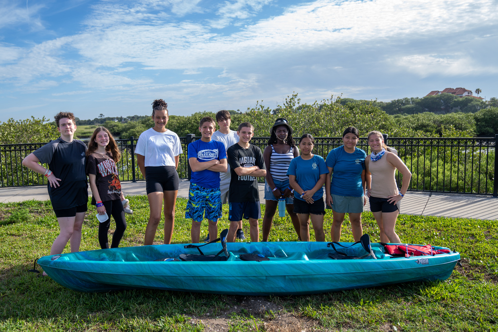 Group photo of the campers behind a blue kayak. 
