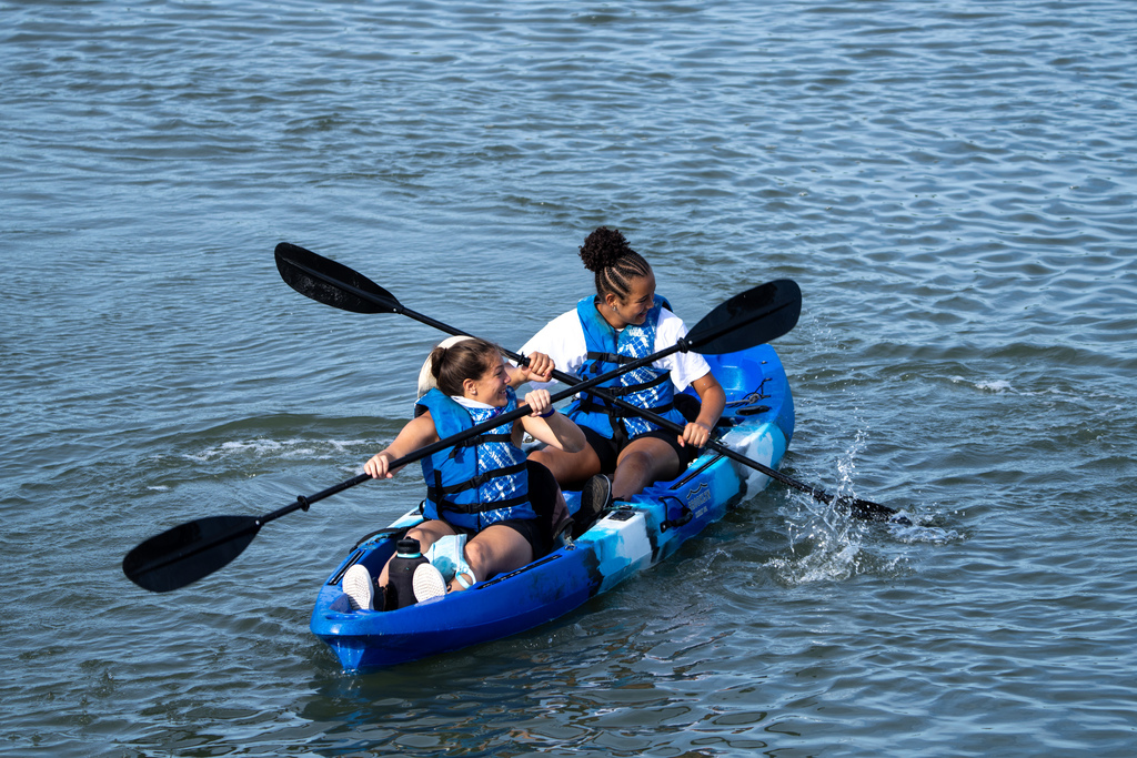 Two campers kayak out on the waters in a blue kayak. 
