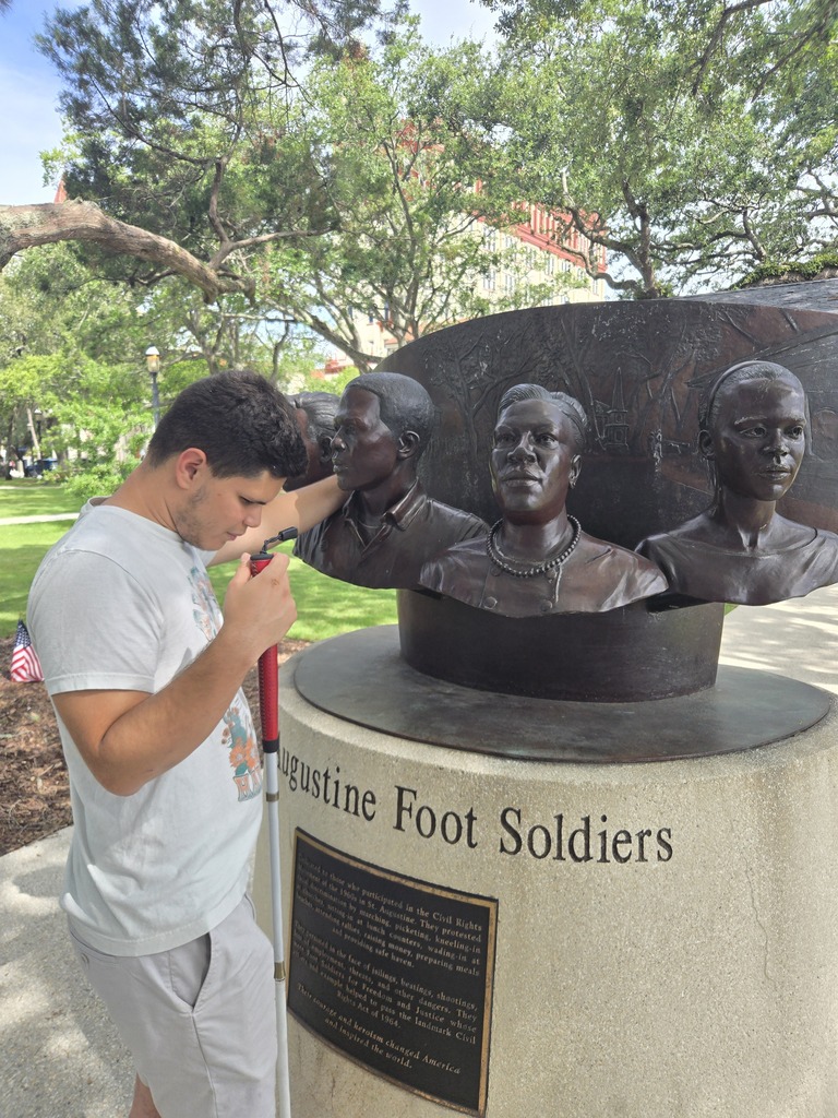 A camper  read the braille about a sculpture in downtown. 