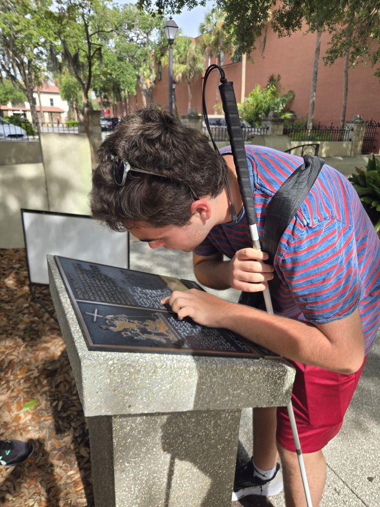 A camper read the braille about a sculpture in downtown. 