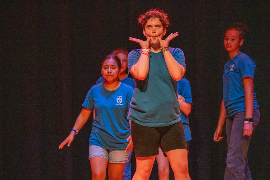 A camper is being silly on stage in the music building.