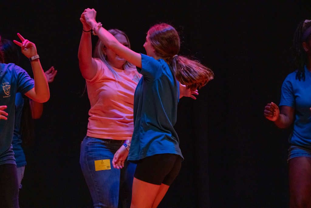 A camper dances with her Mom on stage in the Music Building.