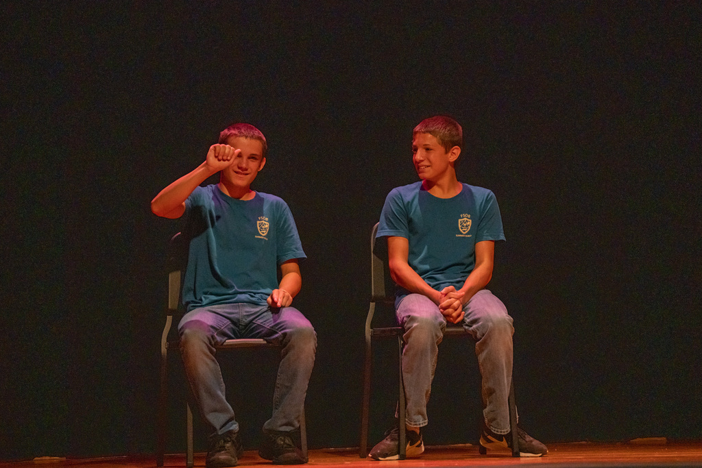 Two campers act on stage in the music building.