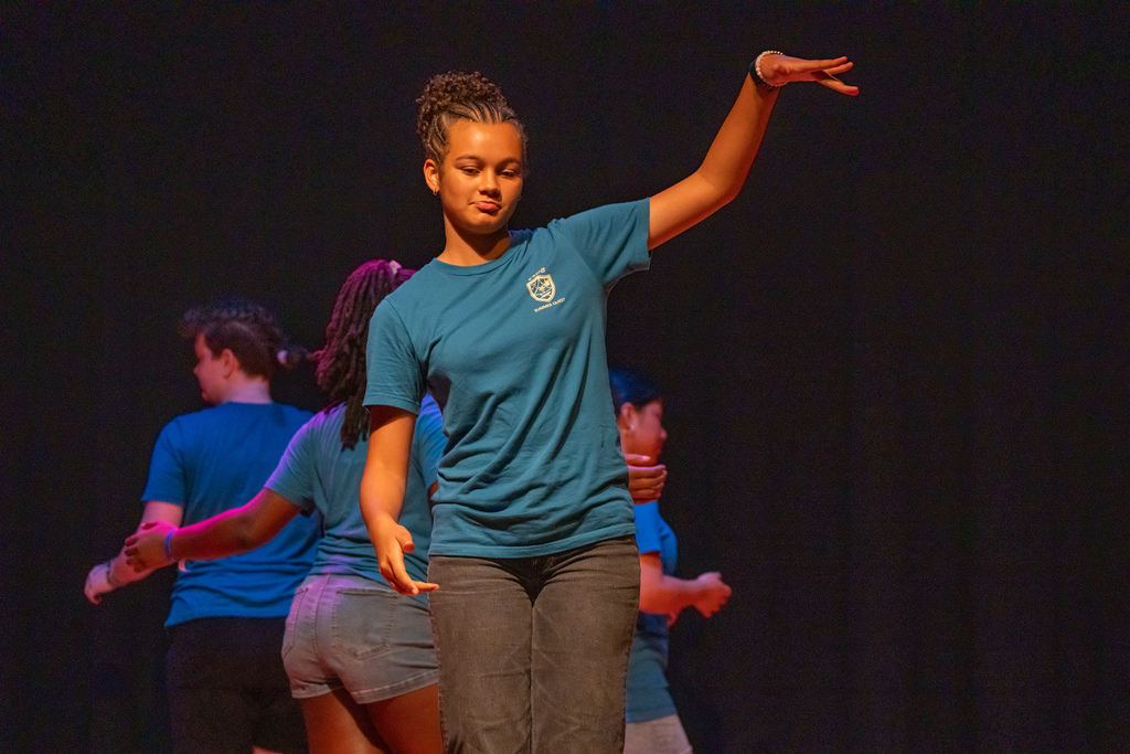 A camper dances on stage in the music building.