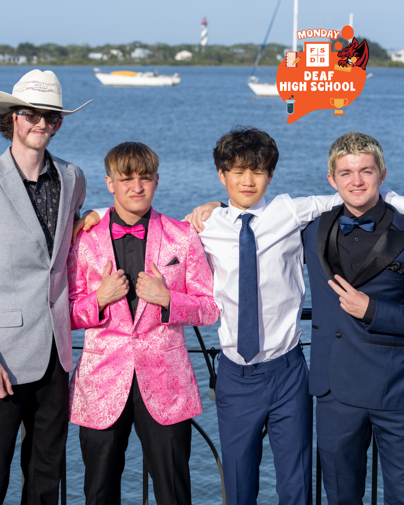 Four high schoolers dressed for prom smile for a photo together outside by the water downtown St Augustine.