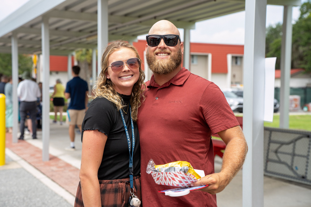 Two staff members smile for their photo together outside.