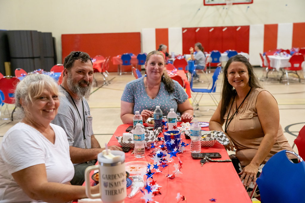 Group of staff members smile for their photo as they eat their meals inside the gym.