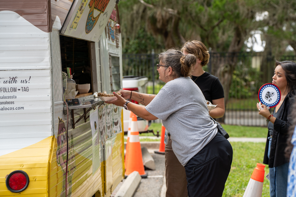 A staff member receives her meal from a food truck outside.