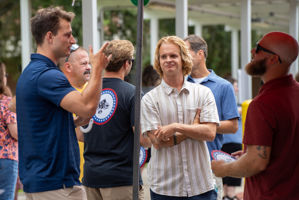 Group of staff members chat and catch up while waiting for their food outside.
