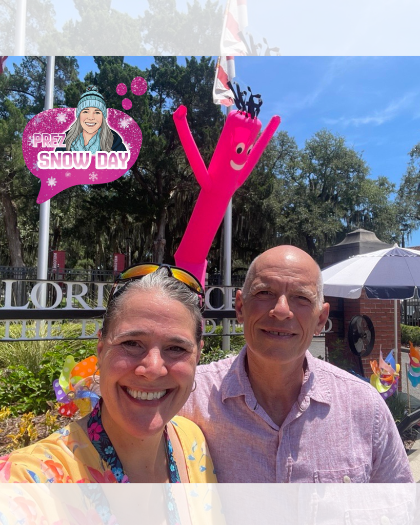 Photo Description: President Snow and her husband, David, pose for a selfie in front of the FSDB sign at Palm Row. Seen in the background are colorful pinwheels and a giant, pink wacky waving inflatable tube man greeting families to the beautiful campus.