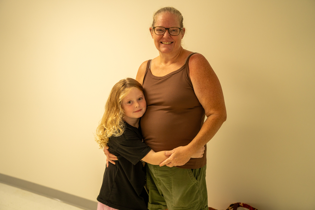 A student hugs her mom inside the hallway of a building.