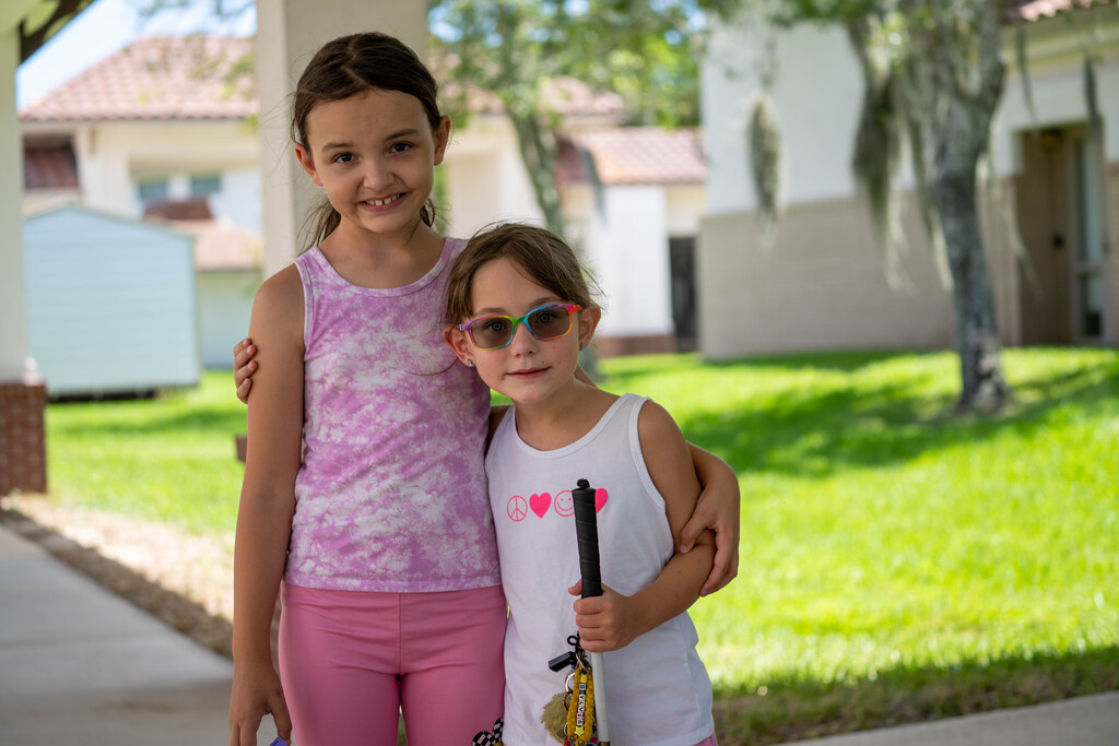 Two sisters smile together for a photo outside.