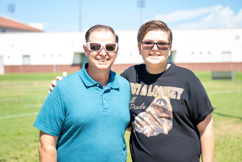 A student smiles with his dad outside.
