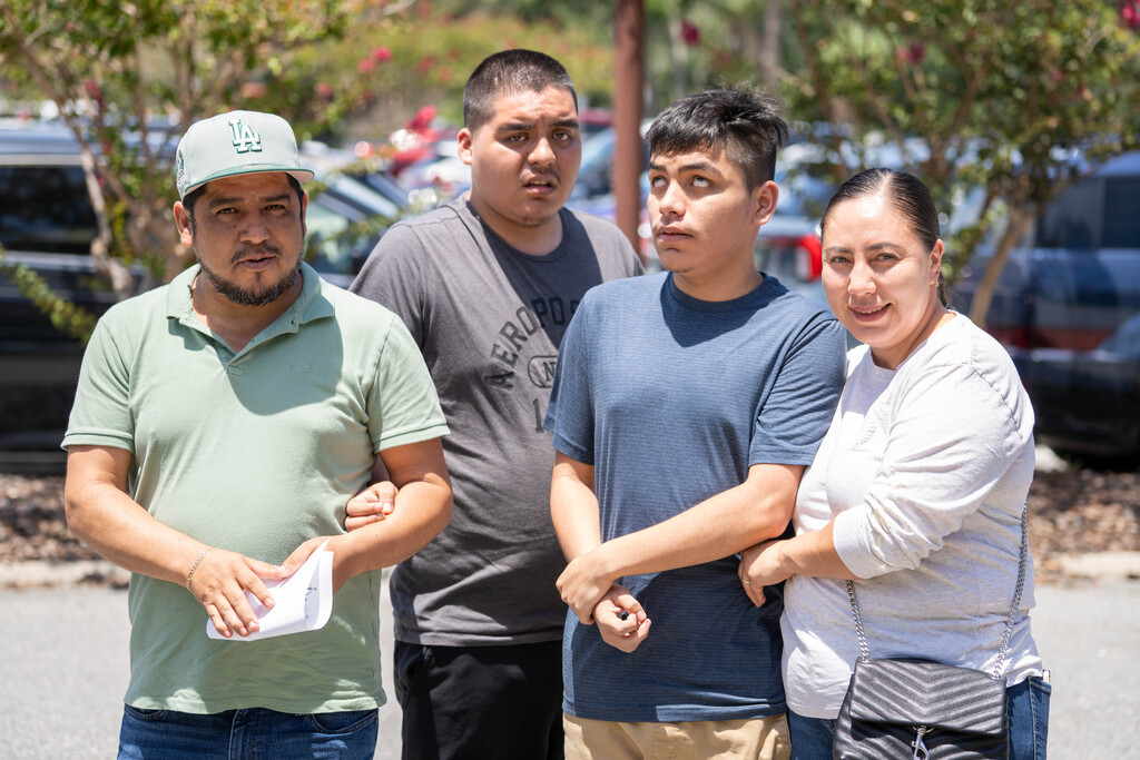 A student smiles with his family outside.