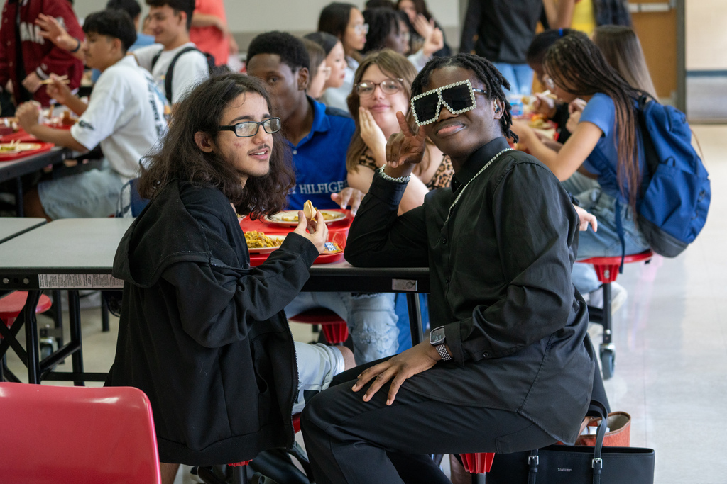 Two students smile for their photo at a table inside the cafeteria.