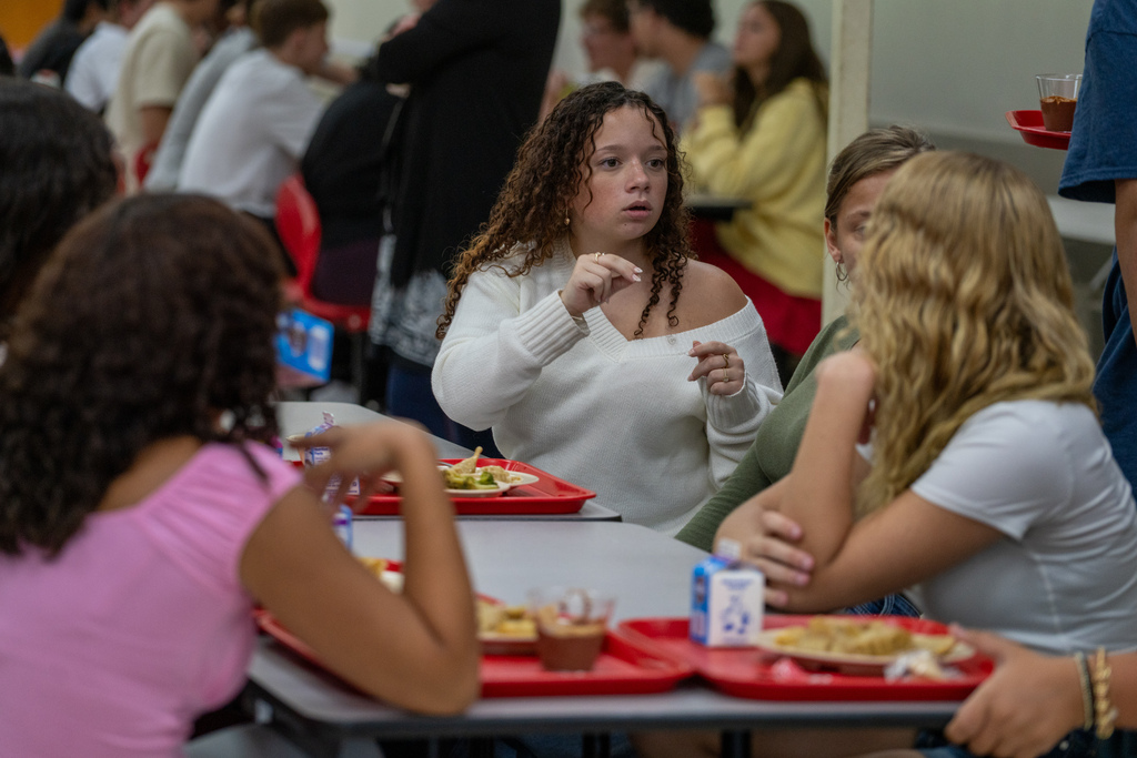 A student signing with her friends inside the cafeteria.