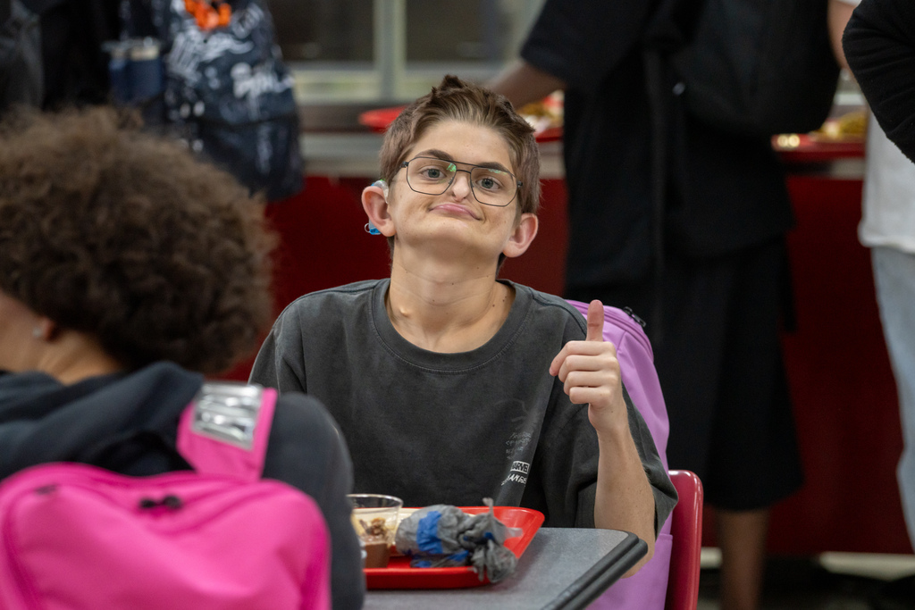 A student gives a thumbs up for the photo inside the cafeteria.