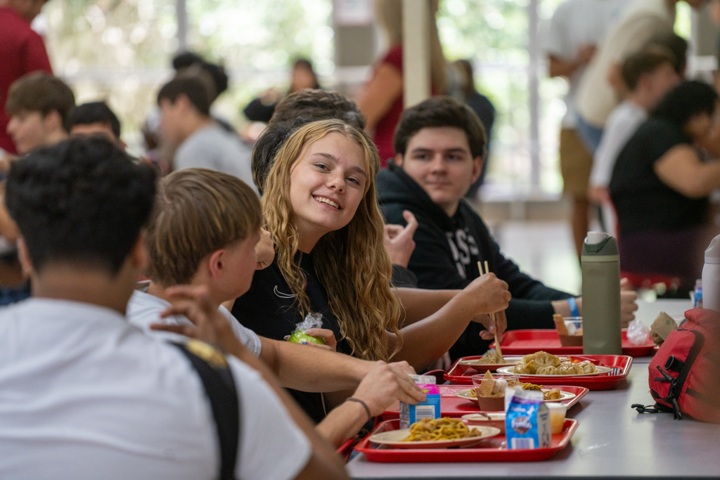 A student smiles at her table inside the cafeteria.