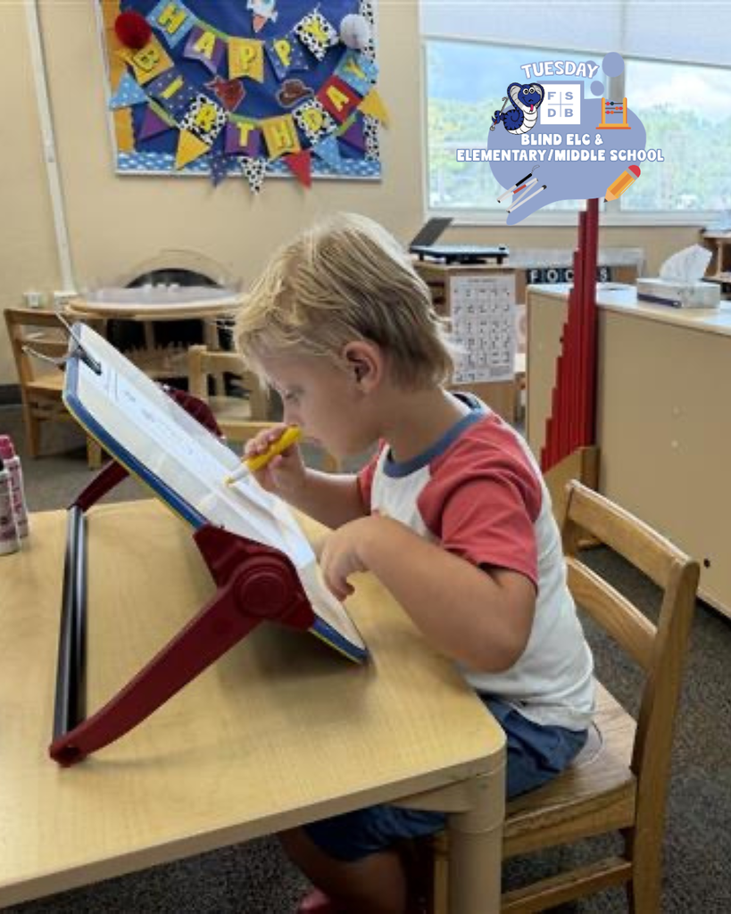 A student is working on writing the letter A on the desk in the classroom.