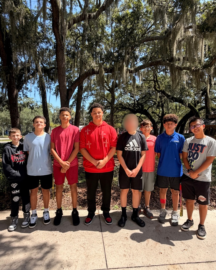Eight DMS boys stand in a line outside for a group photo.
