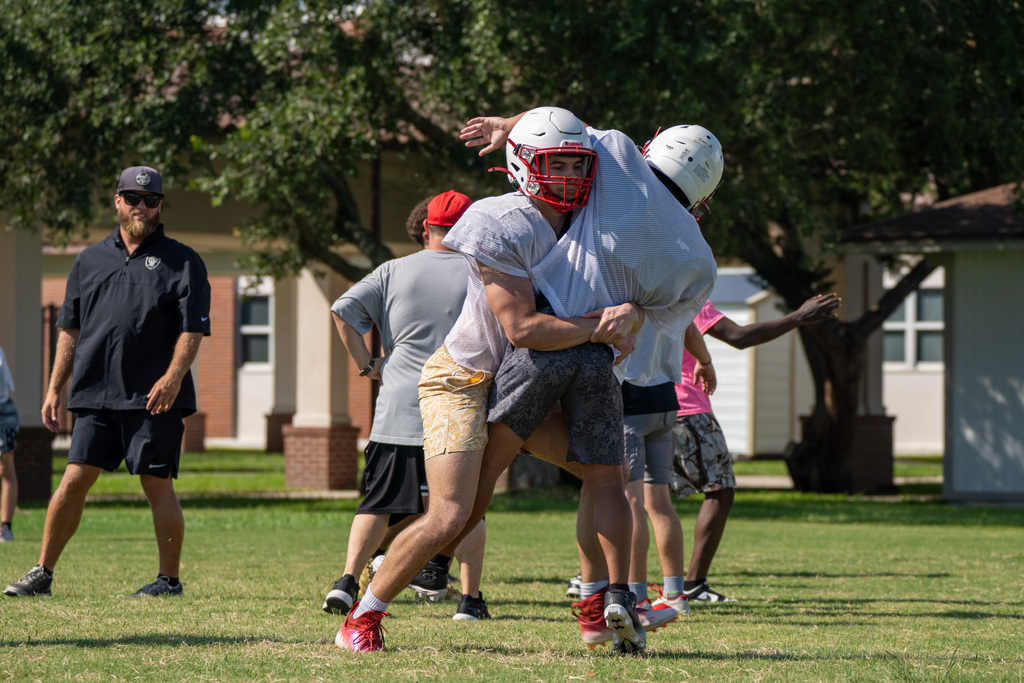 Football players tackle each other outside on the field..