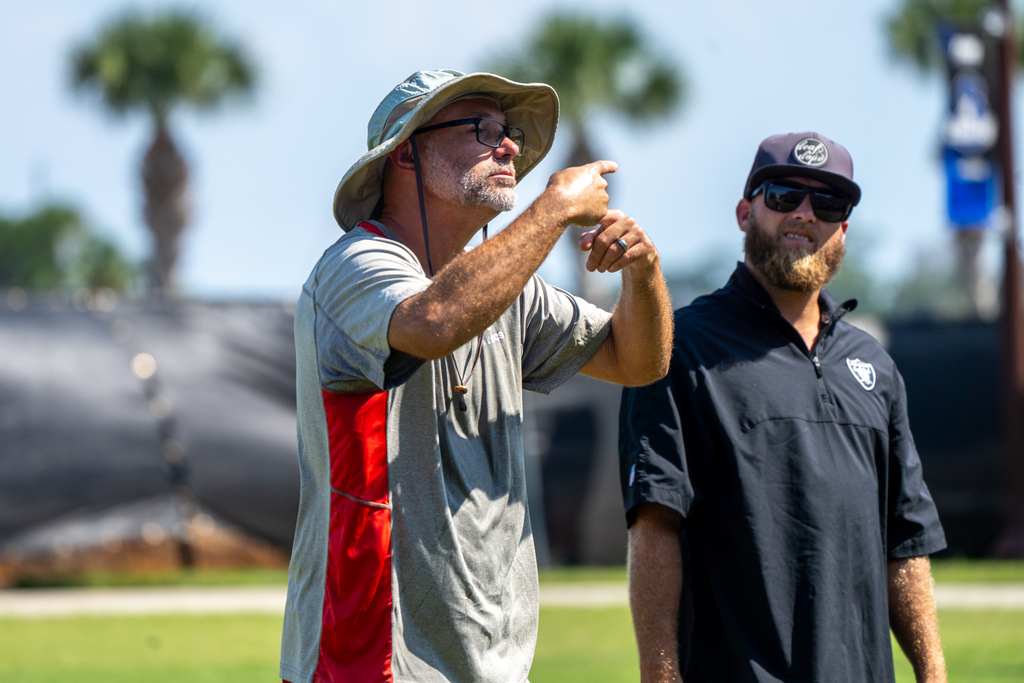 Two football coaches talk to the players.