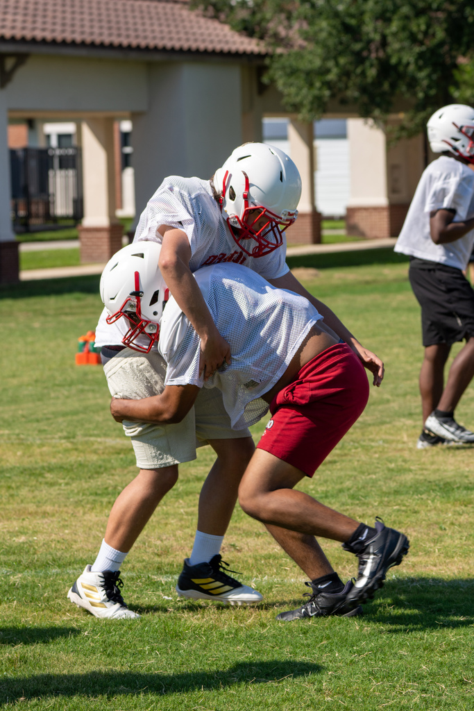 Two football players tackle each other outside on the field.