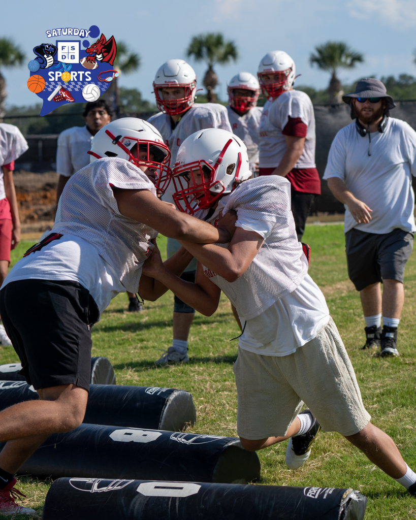 Football players practicing tackling each other outside on the field.