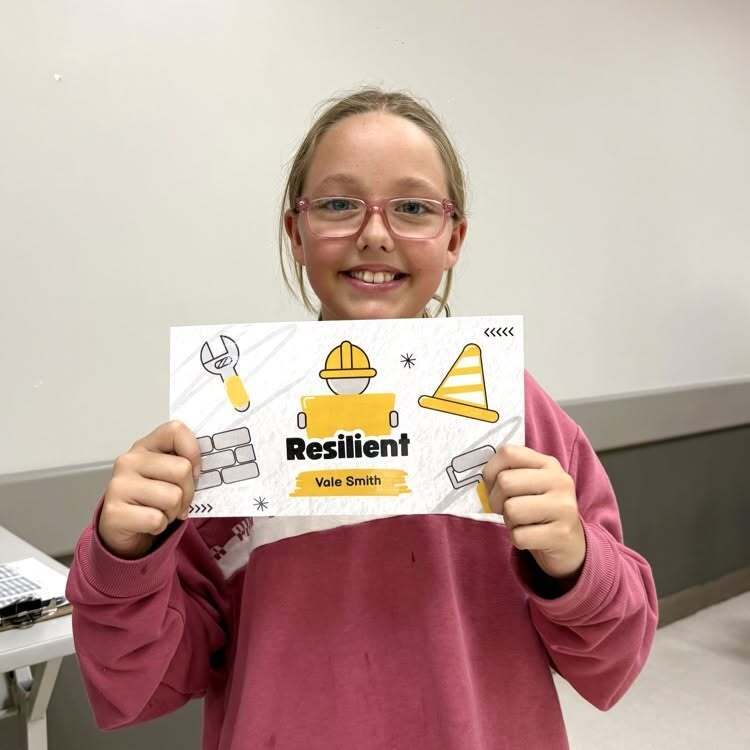 A student smiles with her recognition paper inside the cafeteria.