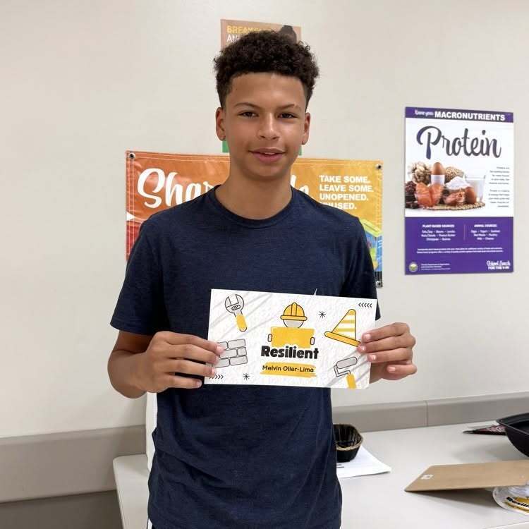 A student smiles with his recognition paper inside the cafeteria.
