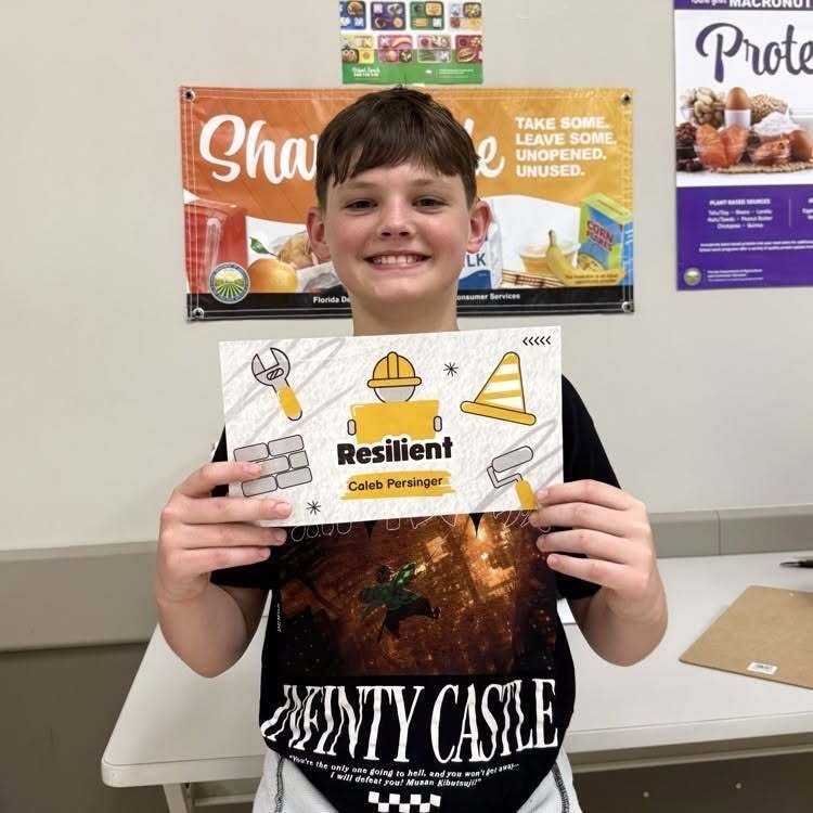 A student smiles with his recognition paper inside the cafeteria.
