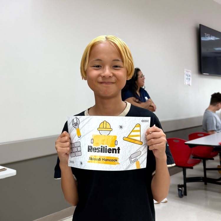 A student smiles with his recognition paper inside the cafeteria.
