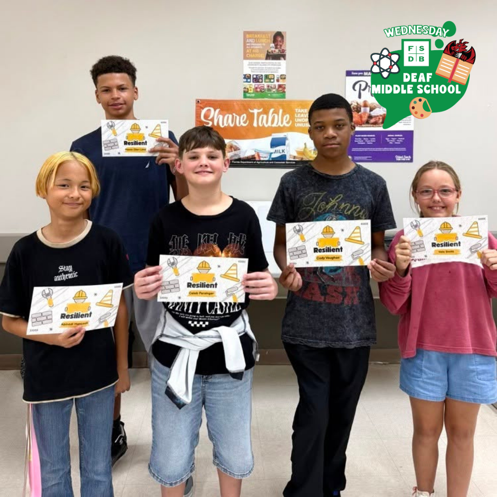 Five students hold their recognition paper and smiles for a photo inside the cafeteria.