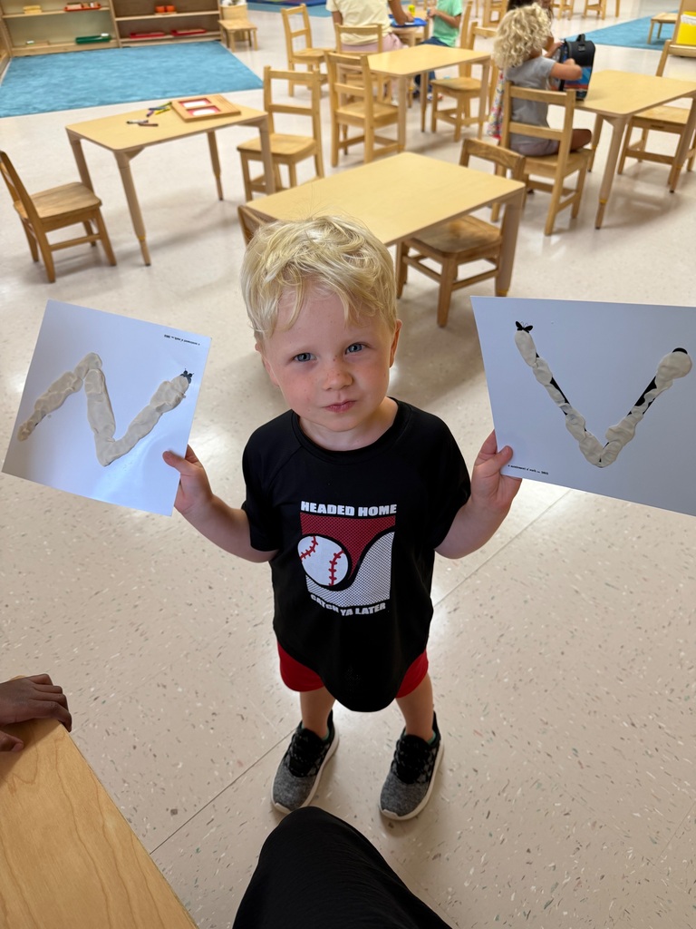 Student holds two papers that show the letter N and V smiles for his photo. 